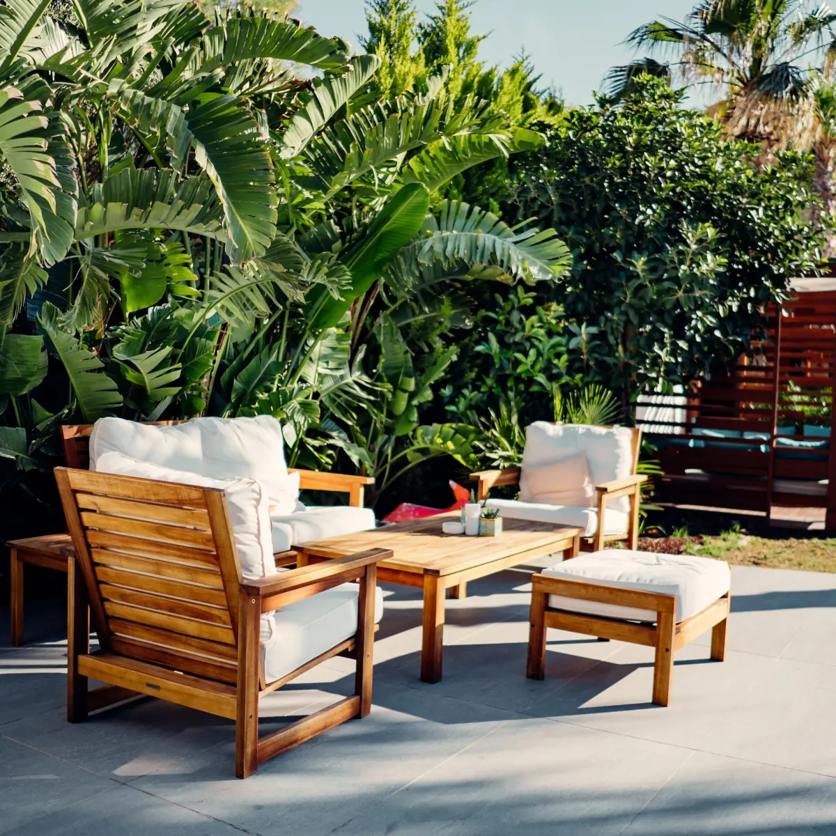 Teak chairs and table in a planted garden
